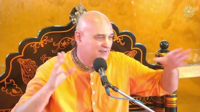 His Grace Gokula Candra Das speaking from an asana with a microphone