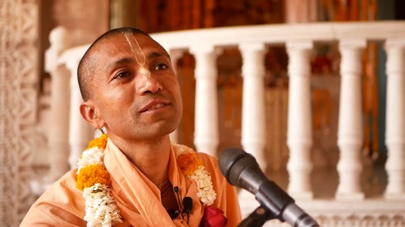 His Grace Savyasachi Das speaking with a microphone in a temple setting